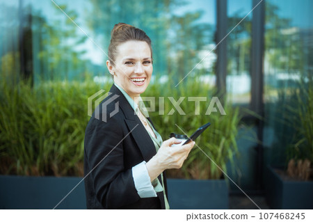 happy female worker in business district using smartphone 107468245