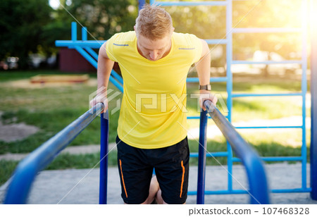 Man pulling up on parallel bars during street training Man pulling up on parallel bars during street training 107468328
