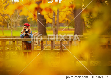 smiling modern woman in jeans shirt and red hat 107469194