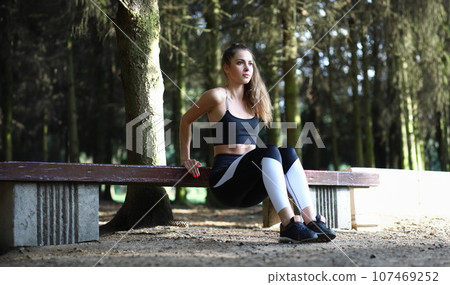 Female trainer goes in for sports outdoors in park 107469252