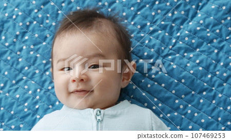 Three month old baby boy smiling and being content on a playmat. 107469253