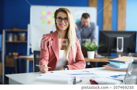 Portrait of smiling business woman in glasses in office 107469288