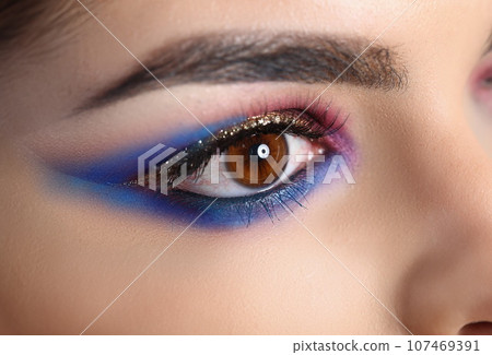 Closeup of brown female eye with beautiful brown red and orange tints smoky eye makeup 107469391