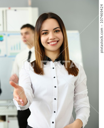Smiling young business woman politely greets company office 107469424