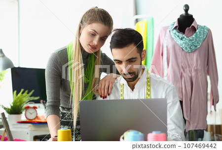 Man and woman stylist designer work on laptop consulting client online in workshop Man and woman stylist designer work on laptop consulting client online in workshop 107469442