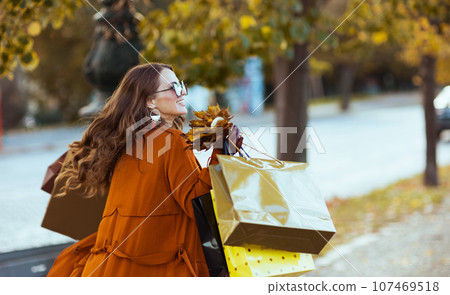 smiling stylish female in orange trench coat smiling stylish female in orange trench coat 107469518