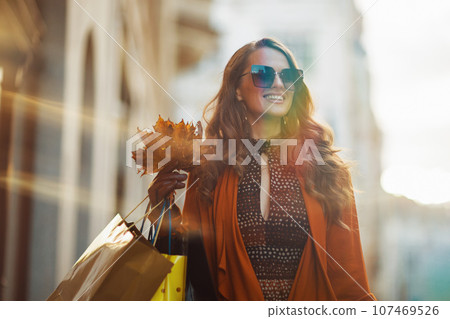 smiling stylish female in orange trench coat 107469526