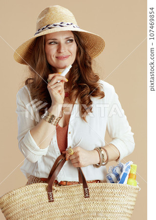 happy stylish female in blouse and shorts against beige 107469854