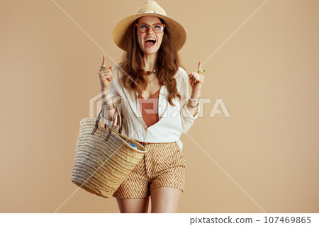 happy 40 years old housewife in blouse and shorts against beige 107469865