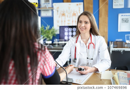 Beautiful female doctor working with patient measures blood pressure 107469896