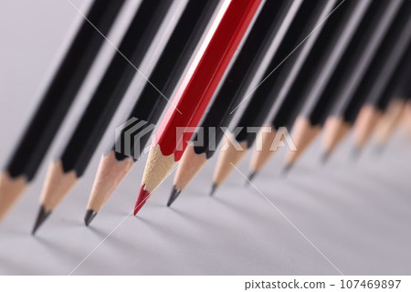 Red pencil separating row of black pencils 107469897