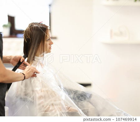 Hairdresser hands cut hair of client in beauty salon 107469914