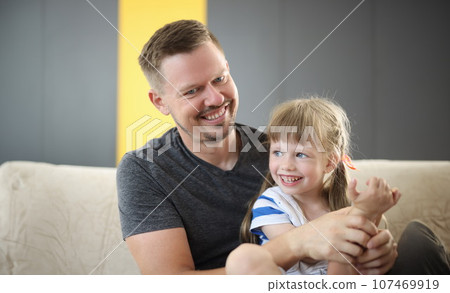 Happy dad holding cute cheerful daughter laughing and having good time together 107469919