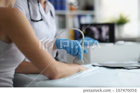 Doctor makes ultrasound of wrist in clinic closeup Doctor makes ultrasound of wrist in clinic closeup 107470058