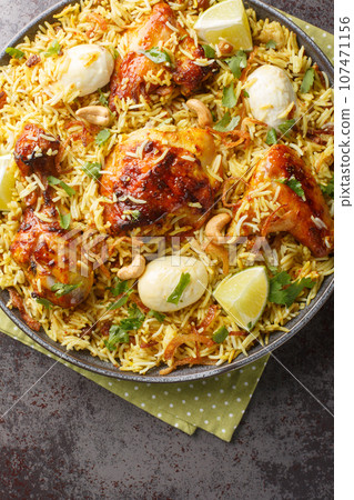Morog Polao tender chicken cooked in ghee and flavored with a variety of spices, layered with aromatic Basmati rice closeup on the plate. Vertical top view Morog Polao tender chicken cooked in ghee and flavored with a variety of spices, layered with aromatic Basmati rice closeup on the plate. Vertical top view 107471156