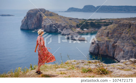 Nice Happy Female Enjoying Sunny Day on Greek Islands. Travel to Greece, Mediterranean islands outside tourist season. Enjoying life and looking at the sea. Turquoise sea background. 107472173