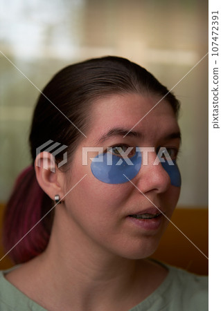 Woman is using cosmetic patches on face. 107472391