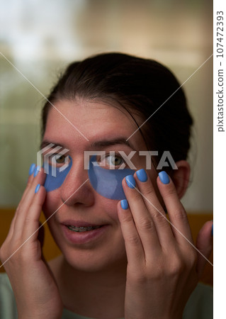 Woman is using cosmetic patches on face. 107472393