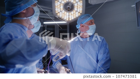 Male surgeons operate patient using laparoscopy instruments Male surgeons operate patient using laparoscopy instruments 107473381