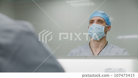 Male medic cleans hands before surgical operation 107473415
