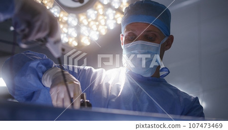 Close up of adult male medic assisting surgeon during surgery Close up of adult male medic assisting surgeon during surgery 107473469