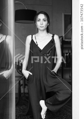 Fashionable woman wearing jumpsuit, posing in stylish boho interior. 107473542