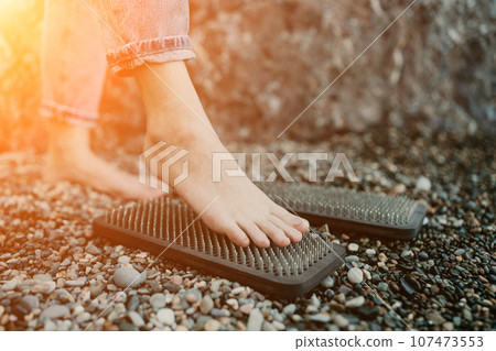 Sea Woman feet stepping on sadhu board during indian practice on the seashore. . Healthy lifestyle concept. tool for working out your inner state Sea Woman feet stepping on sadhu board during indian practice on the seashore. . Healthy lifestyle concept. tool for working out your inner state 107473553