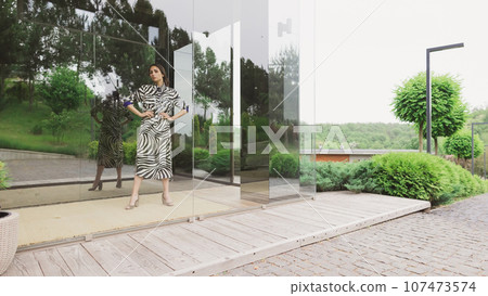 High fashion photo of a beautiful elegant young woman in a pretty zebra print dress posing outdoor. Slim figure High fashion photo of a beautiful elegant young woman in a pretty zebra print dress posing outdoor. Slim figure 107473574