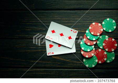 Poker game with one pair combination. Chips and cards on the black vintage table in poker club. Free dark space for advertising. Poker game with one pair combination. Chips and cards on the black vintage table in poker club. Free dark space for advertising. 107473768