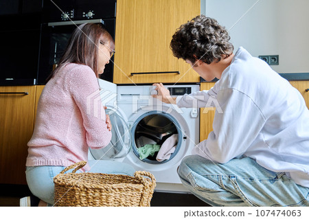 Family mother and teenage son together, at home near washing machine Family mother and teenage son together, at home near washing machine 107474063