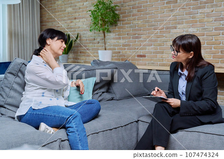 Mature 50s woman having therapy session with psychologist, in office Mature 50s woman having therapy session with psychologist, in office 107474324