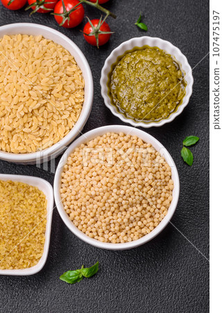 Raw whole grain orzo pasta as an ingredient for a delicious dish 107475197