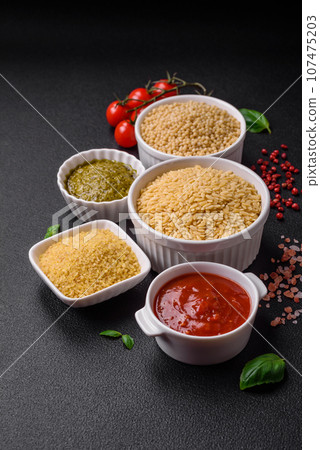 Raw whole grain orzo pasta as an ingredient for a delicious dish 107475203