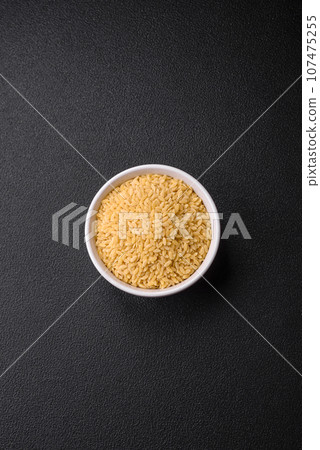 Raw whole grain orzo pasta as an ingredient for a delicious dish Raw whole grain orzo pasta as an ingredient for a delicious dish 107475255