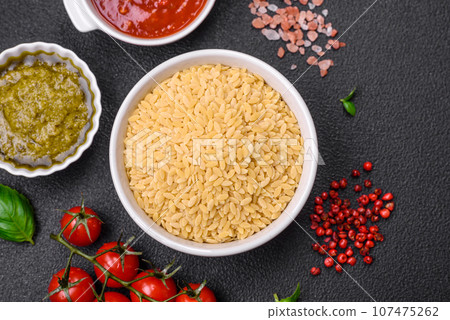 Raw whole grain orzo pasta as an ingredient for a delicious dish 107475262