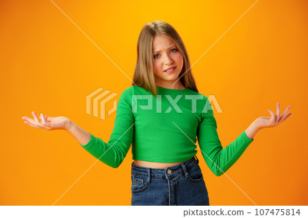 Puzzled teen girl don't know what to do on yellow background in studio 107475814