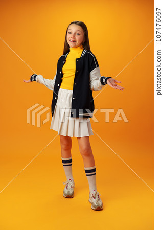 Puzzled teen girl don't know what to do on yellow background in studio 107476097