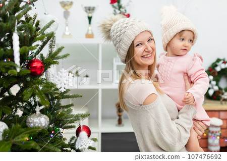 Smiling woman holds tiny baby dressed in pink in her arms 107476692