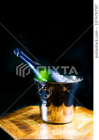 Bottle and cup of champagne on wooden table, dark background Bottle and cup of champagne on wooden table, dark background 107476797