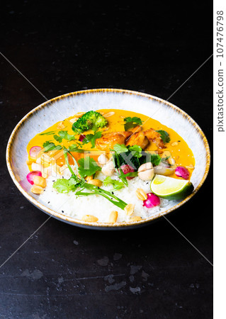 Thai chicken and peanut curry with rice, dark background, top view. Asian cuisine concept. Thai chicken and peanut curry with rice, dark background, top view. Asian cuisine concept. 107476798