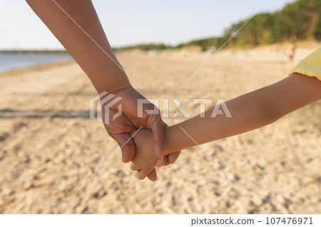 Children's hand and palm in daddy's hand on beach on sunny day. Children's hand and palm in daddy's hand on beach on sunny day. 107476971