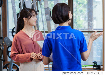 一位女士正在接受有關私人健身房的解釋 一位女士正在接受有關私人健身房的解釋 107478319