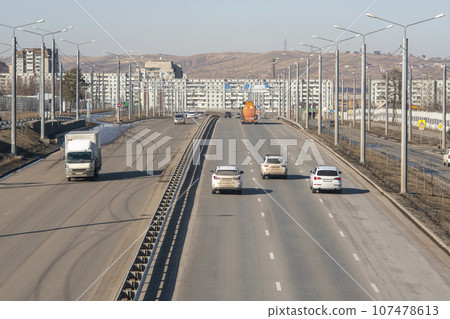 Multi-lane road with a dividing strip against the backdrop of the city. 107478613