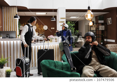 Arrival at modern hotel lobby, check-in, cozy lounge, luxury resort, winter gear, recreation, relaxation, exclusive holiday. Youthful tourists in lounge area awaiting accommodation. 107479506