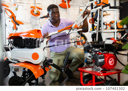 Man choosing cultivator in gardening tools store 107481302