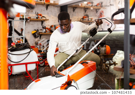 Male customer examining lawnmowers in equipment shop Male customer examining lawnmowers in equipment shop 107481433