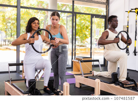 Positive woman and African American man training with pilates ring Positive woman and African American man training with pilates ring 107481587
