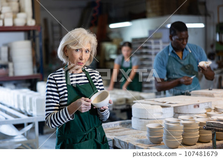 Portrait of positive senior woman potter with bowl 107481679