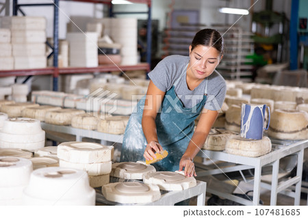 Woman potter polishing new crafted plates 107481685