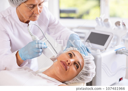 Young woman undergoing facial skin cleansing with ultrasonic shovel Young woman undergoing facial skin cleansing with ultrasonic shovel 107481966